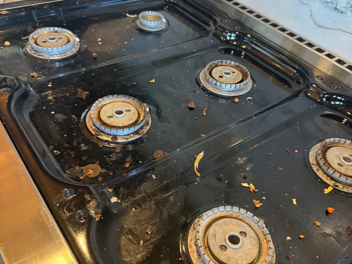 Burnt-on grease on a stovetop before deep cleaning
